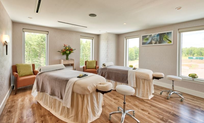 Two massage beds in our spa, dressed in comfortable linens, with windows looking out to the nature of the Catskills.