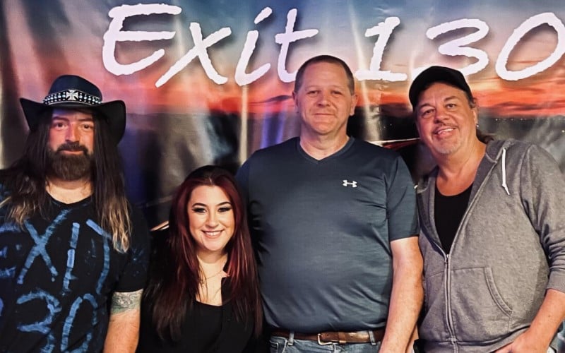 Members of Exit 130 Band standing in front of a banner that says "Exit 130"