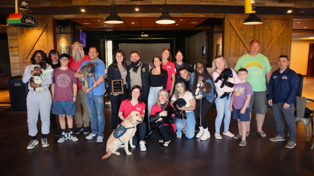 a group photo of people holding puppies
